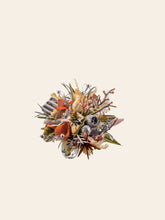 The Virgo Flower Ring by CAMELLIA features a small, colorful bouquet with mixed flowers and greenery in red, orange, yellow, and pink tones, reminiscent of an intricate design against a plain beige background.